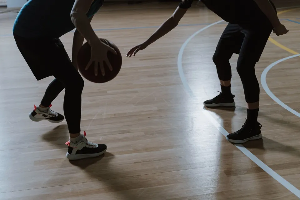 Two players competing for the ball on a hardwood court