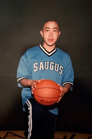 Herman as a teenager in a light blue Saugus jersey, holding a basketball