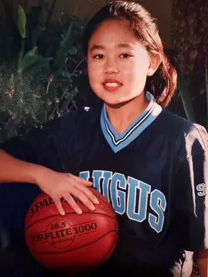 Lelanie as a girl in a navy Saugus jersey, with a basketball