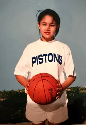 Lelanie as a girl in a Pistons T-shirt, holding a basketball