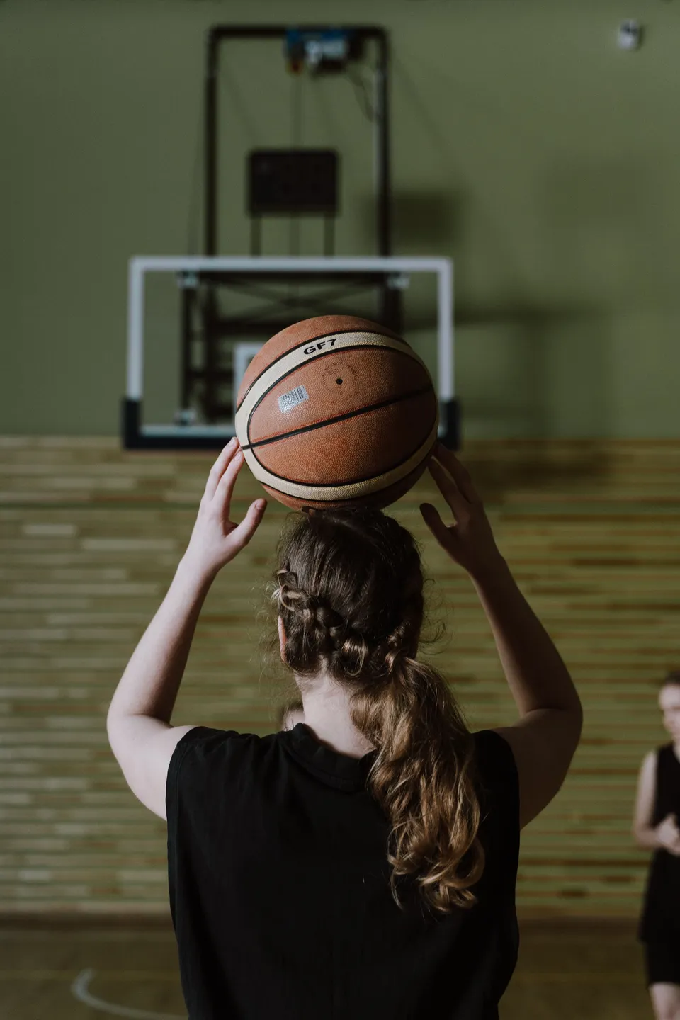 A player seen from behind, lining up a shot in a quiet gym
