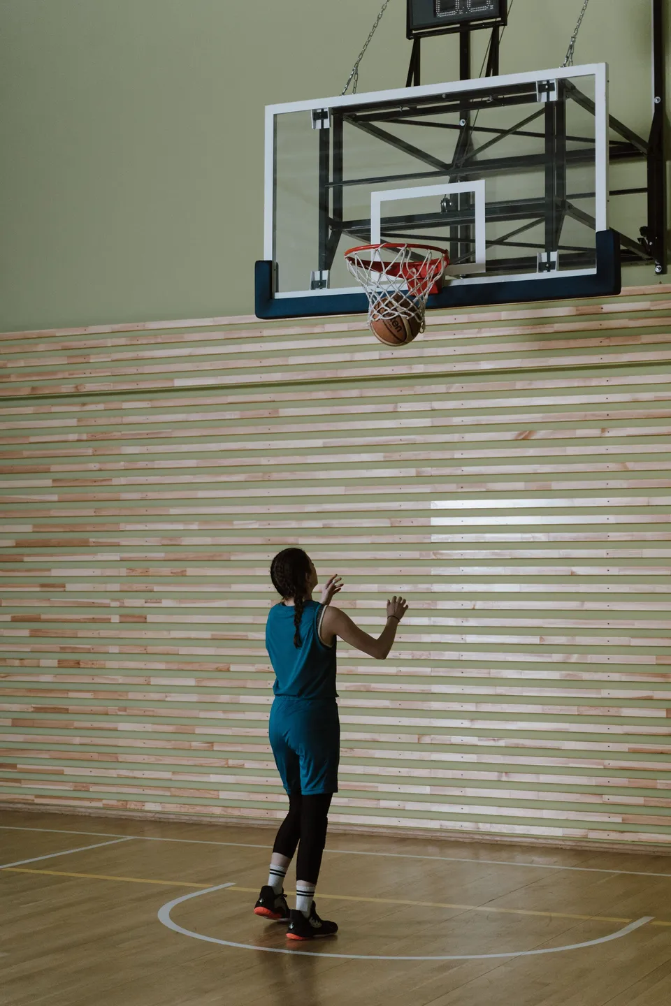 A player in teal watches her shot drop through the net